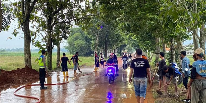 Polri Bersama Damkar dan Warga Bersihkan Tumpahan Tanah Urug Yang Tercecer di Jalan