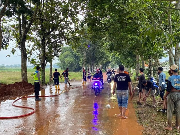 Polri Bersama Damkar dan Warga Bersihkan Tumpahan Tanah Urug Yang Tercecer di Jalan
